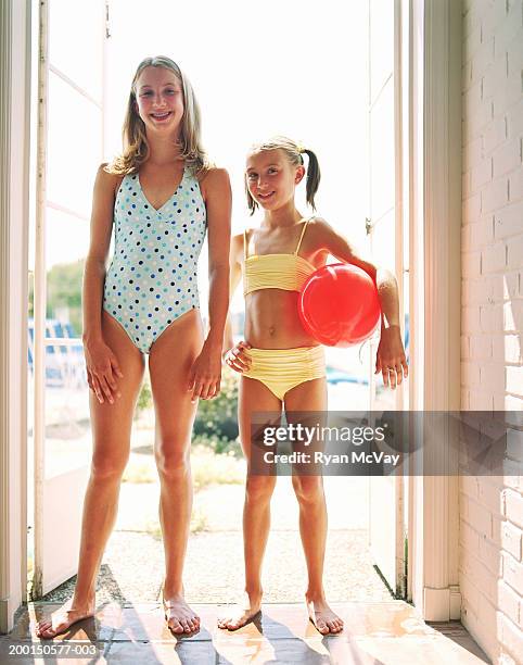 two girls (9-12) wearing swimsuits, standing in doorway, portrait - tween girl swimsuit stockfoto's en -beelden