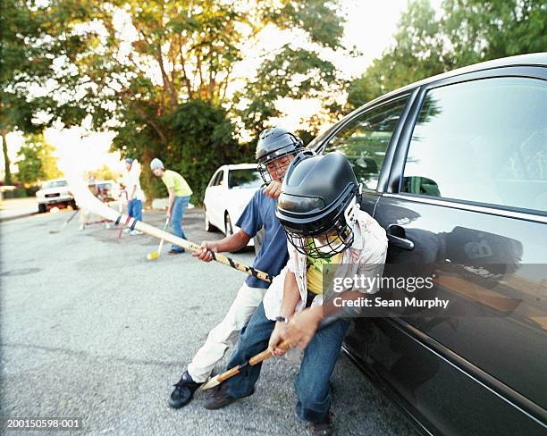 boys (11-15) playing street hockey, leaning against car - hockey car ストックフォトと画像