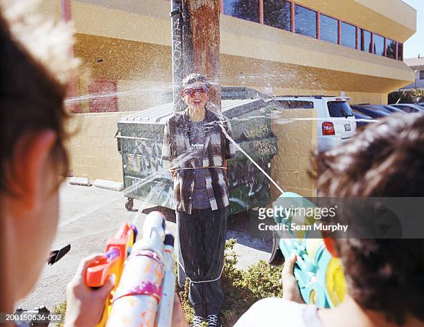 boys (13-15) tied to pole, being hit by friends with water guns - revenge stock pictures, royalty-free photos & images