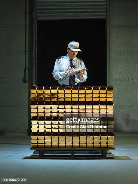 security guard with clipboard and pen by stack of gold bars - ingot stock-fotos und bilder