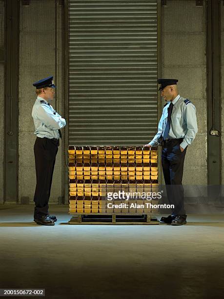 two security guards by stack of gold bars, side view - goldbarren stock-fotos und bilder