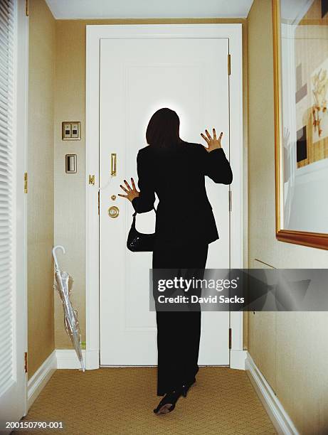 woman looking through door peephole, rear view - peephole stock-fotos und bilder