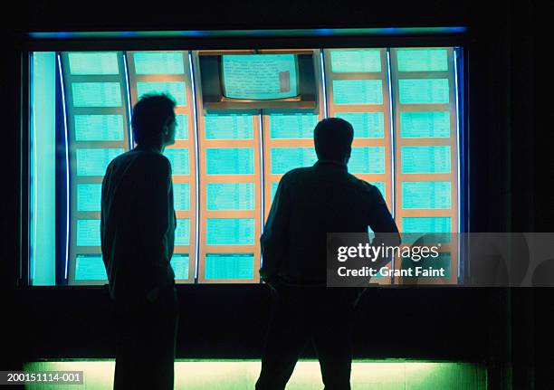 man and teenage boy (15-17) looking at stock market displays, evening - window display stock-fotos und bilder