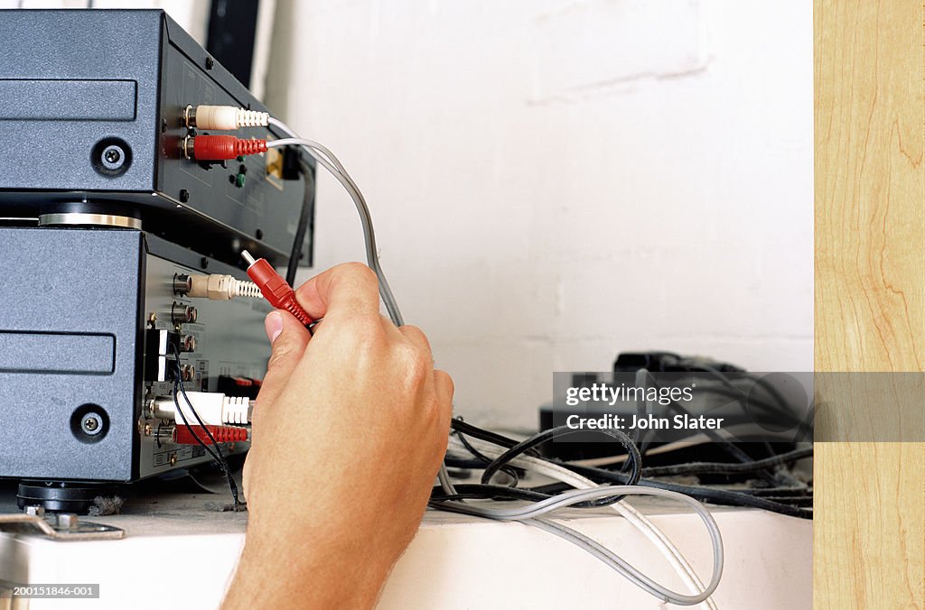 Man attaching cords to back of stereo, close up