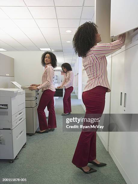 young woman working in office, side view (multiple exposure) - klonen stockfoto's en -beelden