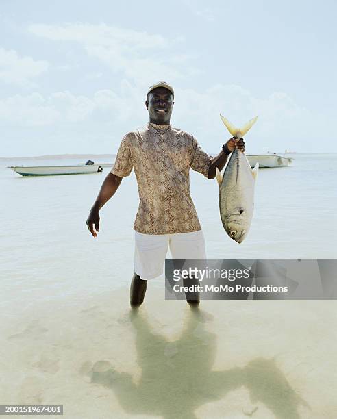 Man standing in ocean holding fish, portrait
