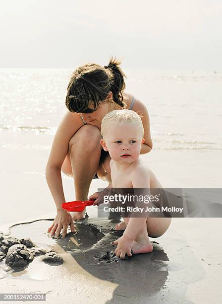 mother and son (18-21 months) on beach, playing in sand - sandy molloy stock pictures, royalty-free photos & images
