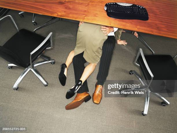 business couple embracing under desk, elevated view - büroaffäre stock-fotos und bilder