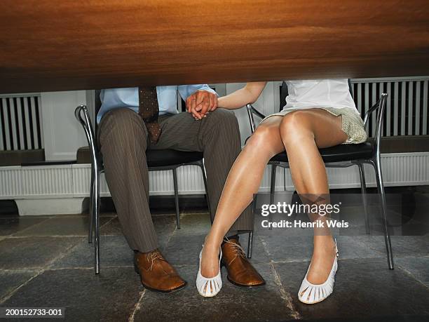 business couple holding hands under desk, low section - under the skirt stock-fotos und bilder