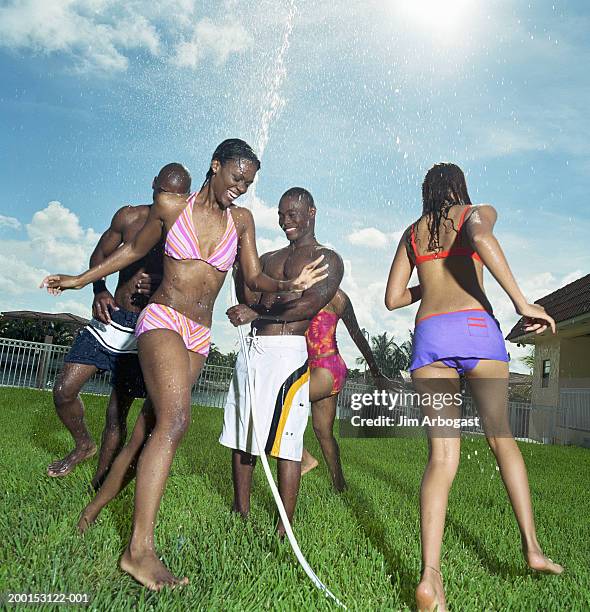 young men and women in bathing suits playing with hose - barefoot black men stock pictures, royalty-free photos & images