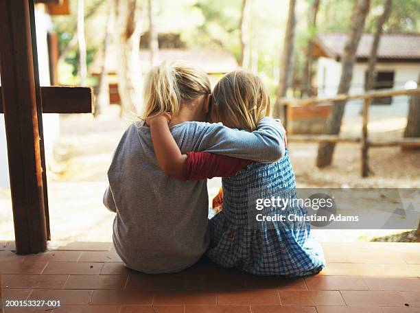 two girls (2-4) embracing on porch, rear view - empatia foto e immagini stock