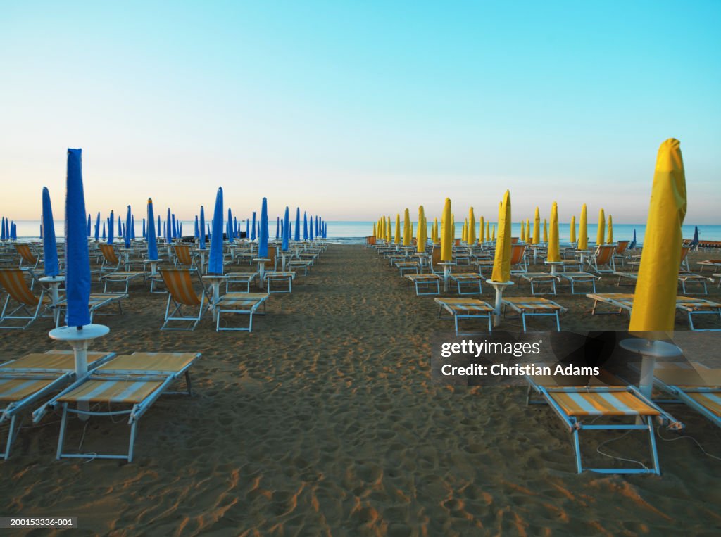 Closed parasols and sunloungers on beach