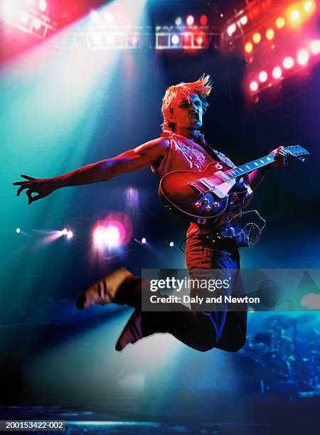 man in air, holding electric guitar on stage - boygroup stock-fotos und bilder