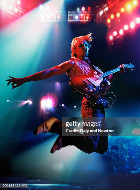 man in air, holding electric guitar on stage - rock music imagens e fotografias de stock
