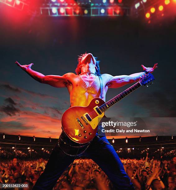 bare chested man with guitar on stage by crowd, arms outstretched - artiste de spectacle photos et images de collection