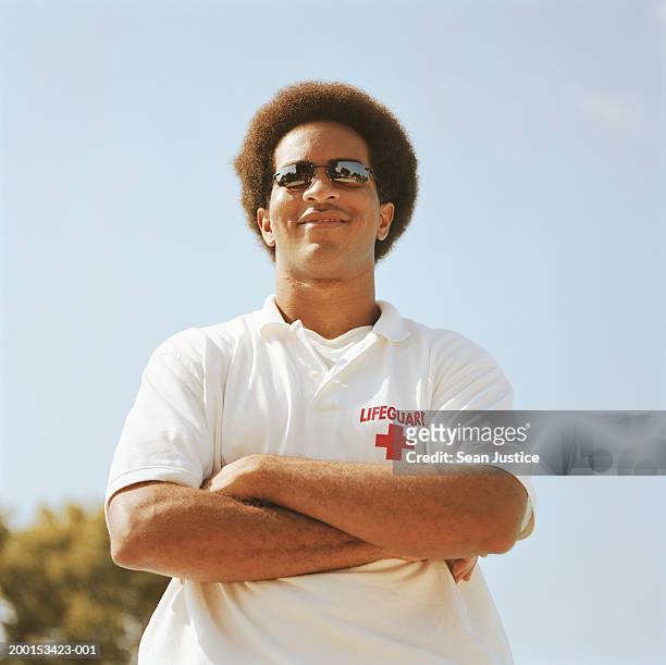 man wearing sunglasses with arms folded, smiling - lifeguard fotografías e imágenes de stock
