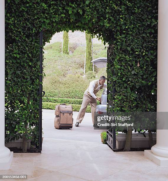 hotel attendant unloading luggage from car - entry car stock pictures, royalty-free photos & images