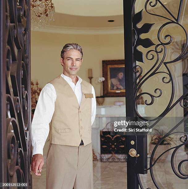 hotel attendant standing in doorway, portrait - ドアマン ストックフォトと画像