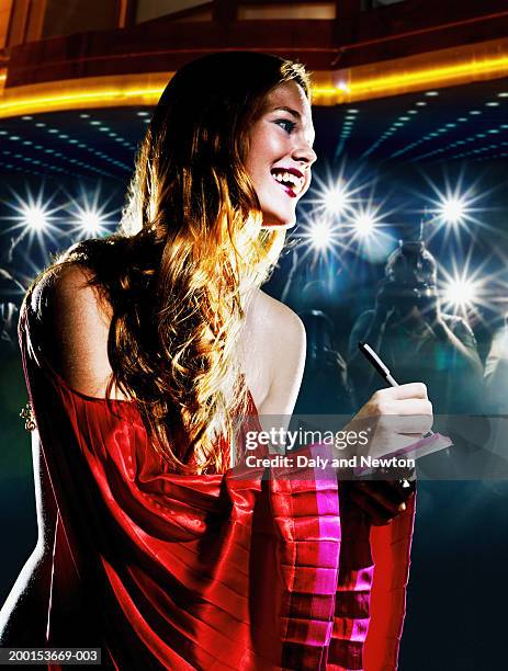 young woman signing autograph, crowd taking photos in background - estréia de filme imagens e fotografias de stock