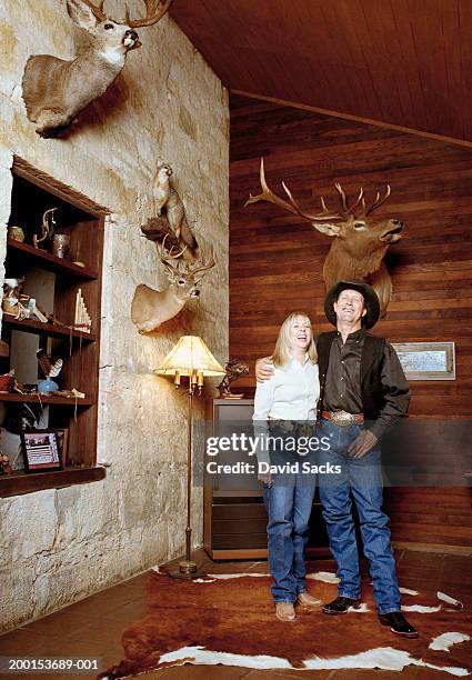 couple in cowboy clothing laughing in living room - trophy shelf stock pictures, royalty-free photos & images