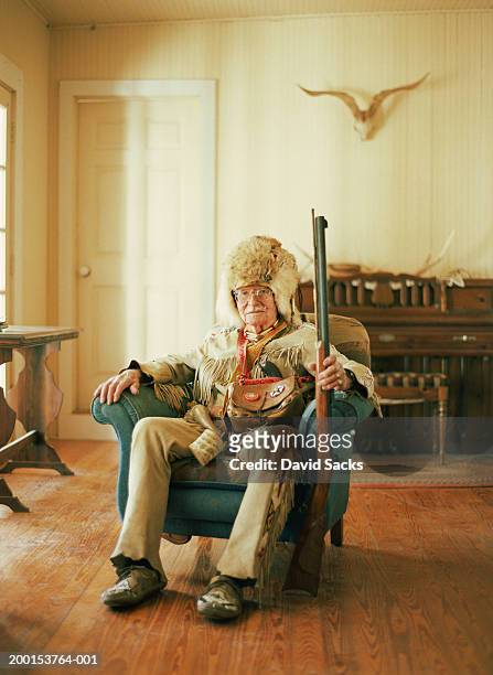 senior man with gun wearing leather and fur hunting clothes, portrait - bontmuts stockfoto's en -beelden