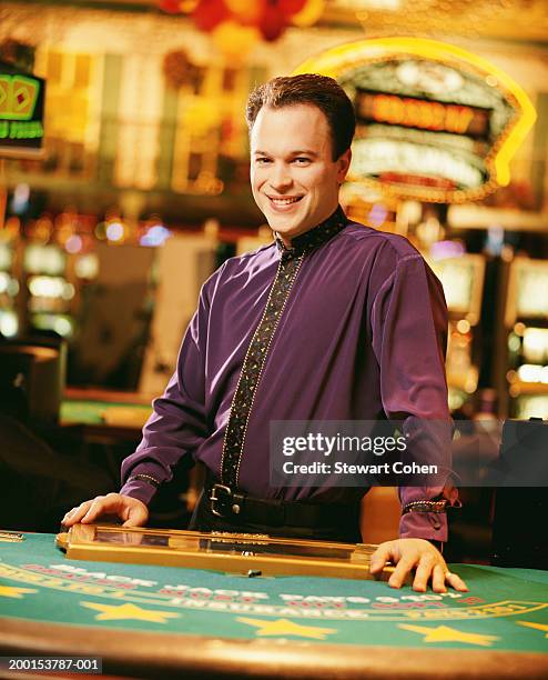 dealer standing behind poker table in casino, portrait - casino worker ストックフォトと画像