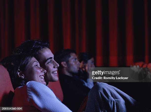 teenage couple (16-18) laughing in auditorium, side view - girlfriends films stockfoto's en -beelden