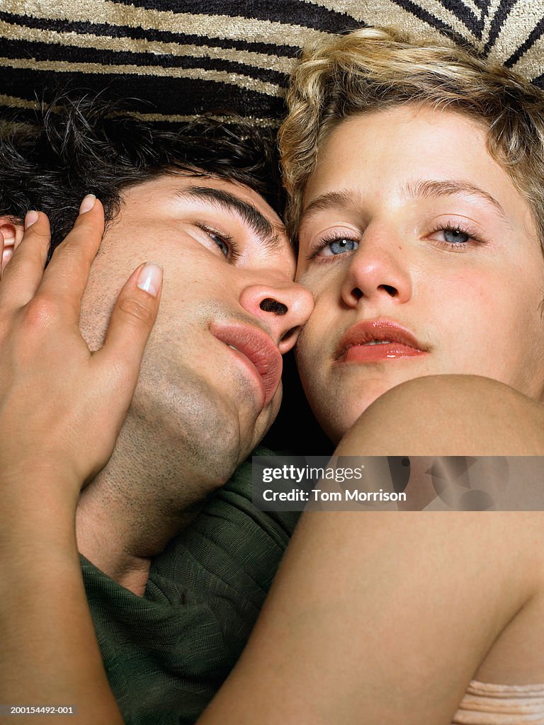 Young couple lying down, embracing, portrait of woman