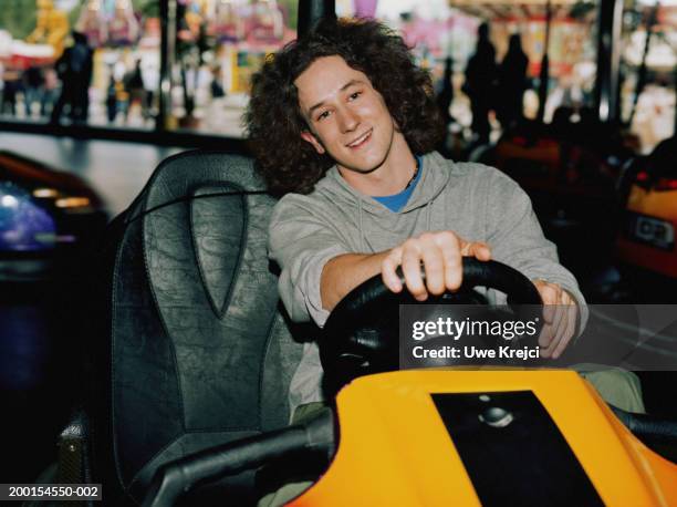 young man driving bumper car, smiling - autoscooter stock-fotos und bilder