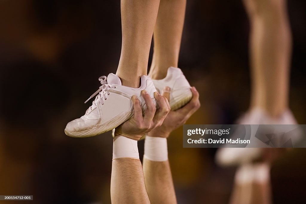 Male cheerleader lifting female cheeleader above his head, close-up