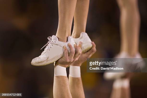 male cheerleader lifting female cheeleader above his head, close-up - white women feet 個照片及圖片檔