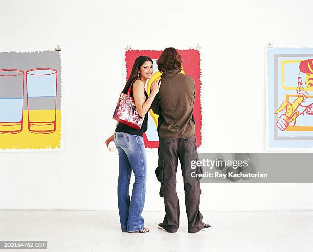 young couple in art gallery, woman with hand on man's shoulder - friends museum fotografías e imágenes de stock