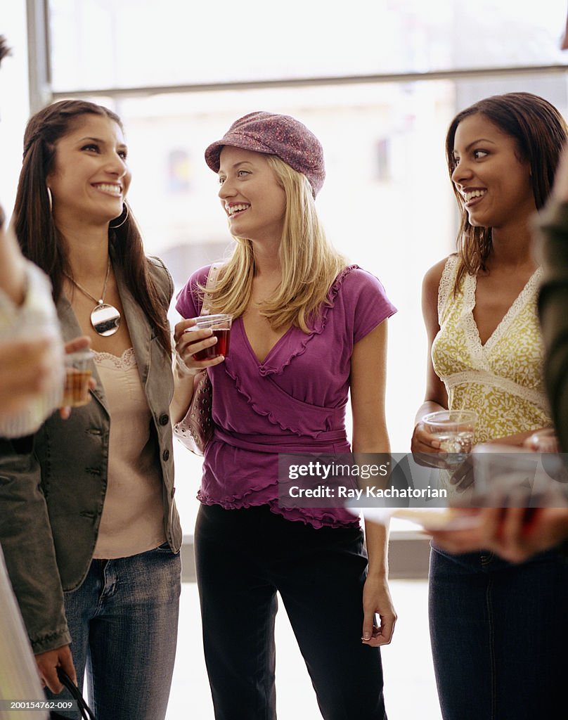 Three young women in art gallery opening