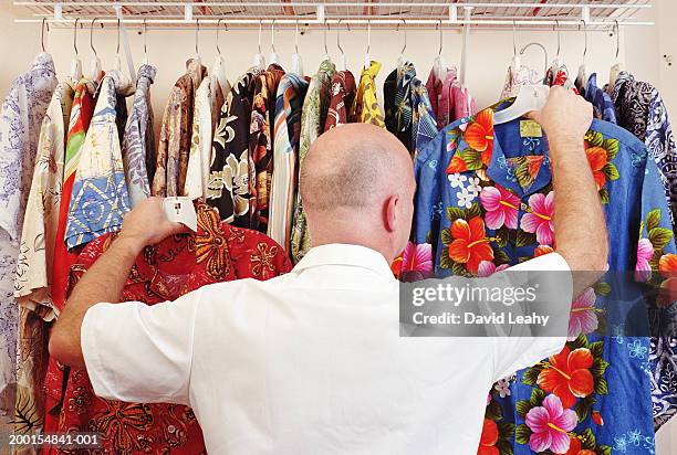 mature man selecting hawaiian shirts from rail, rear view - hawaiian shirt 個照片及圖片檔