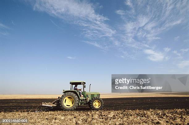 tractor on barren wheat field, autumn, side view - traktor stock-fotos und bilder