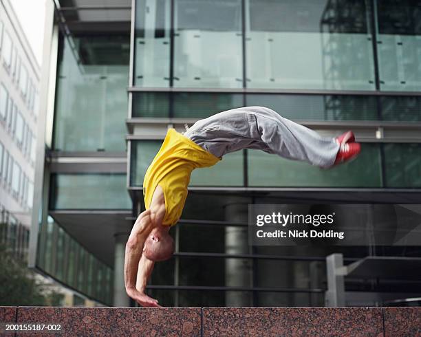 young man performing backflip on wall outdoors (blurred motion) - yellow wall stock-fotos und bilder