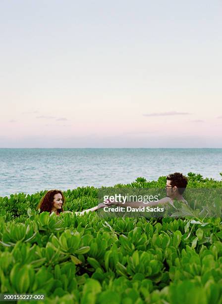 naked couple holding apple in tropical plant field - temptation of eve stock pictures, royalty-free photos & images
