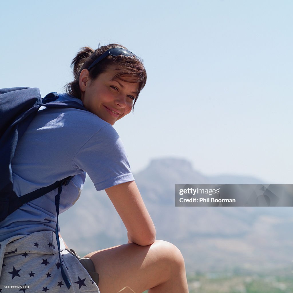 Woman outdoors wearing backpack, looking over shoulder, portrait