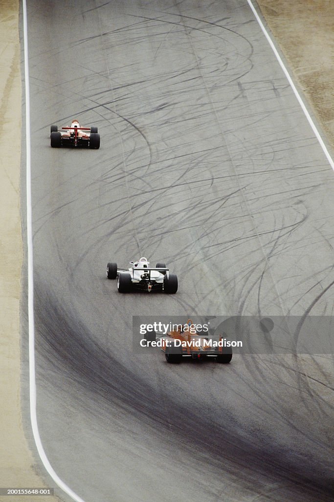 Formula cars circling race track, elevated view  (Digital Enhancement)