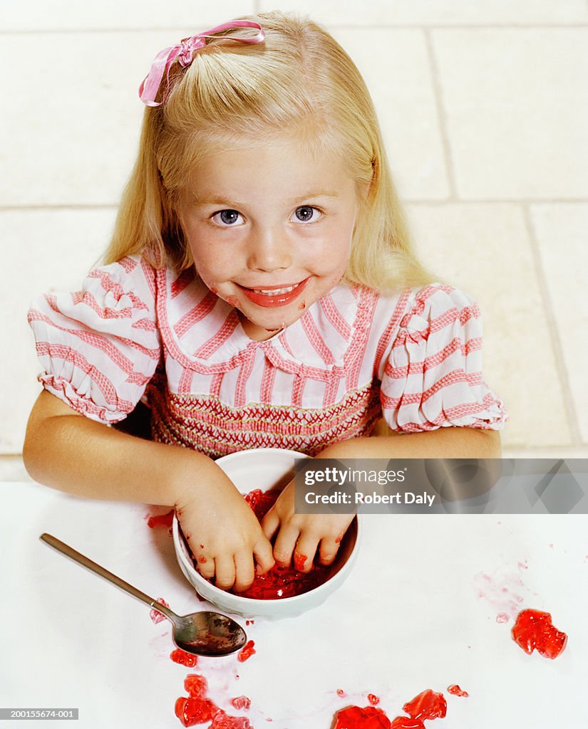 Girl (4-6) with hands in bowl of jelly, portrait, elevated view