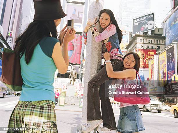 woman taking photo of friends climbing light post - travel11 stock pictures, royalty-free photos & images