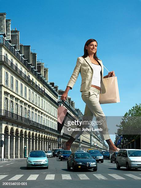 giant woman with shopping bags crossing busy road (digital composite) - géant photos et images de collection