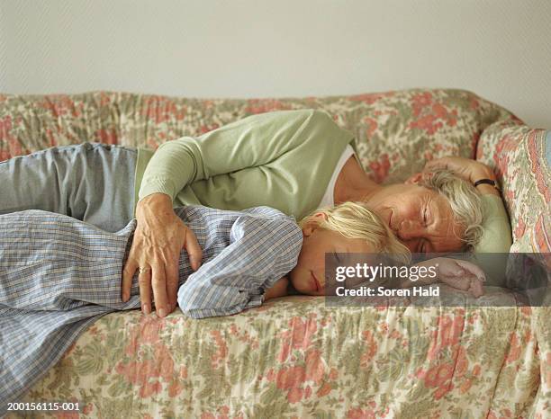 grandmother and granddaughter (6-8) sleeping on sofa - grandma sleeping stockfoto's en -beelden