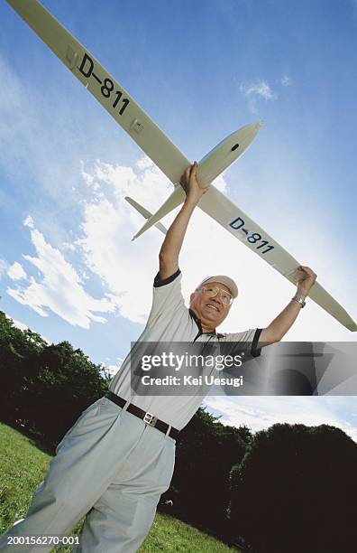 senior man carrying model plane, low angle view - modellflygplan bildbanksfoton och bilder