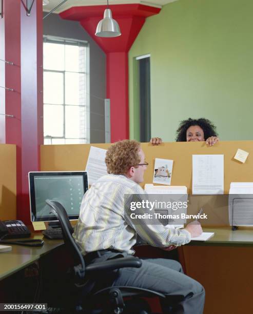 businessman and businesswoman talking to each other over cubicle wall - peeking over stock pictures, royalty-free photos & images