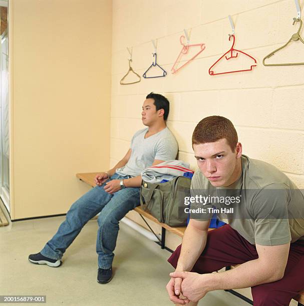 teenage boy (16-18) in changing room, portrait, man in background - young boys changing in locker room stock pictures, royalty-free photos & images