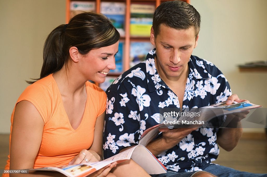 Young couple looking at brochures in travel agency