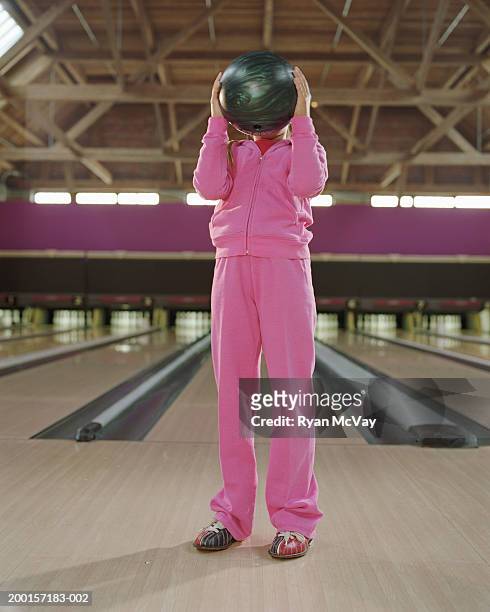 girl (7-9) holding bowling ball in front of face - kids bowling stock pictures, royalty-free photos & images