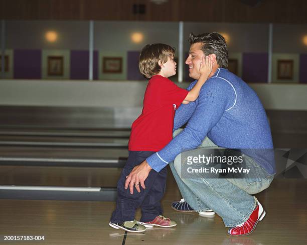 jungen (2-4) berühren vaters gesicht in eine bowlingbahn, seitenansicht - family bowling stock-fotos und bilder