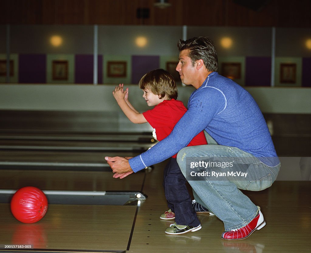 Father teaching son (2-4) how to bowl, side view